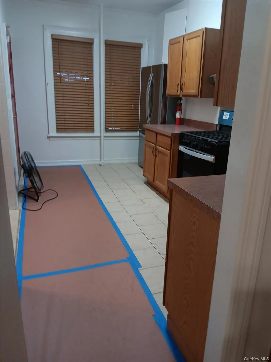 Kitchen with brown cabinetry, black range with gas stovetop, light tile patterned floors, and dark countertops Kitchen with brown cabinetry, black range with gas stovetop, light tile patterned floors, and dark countertops