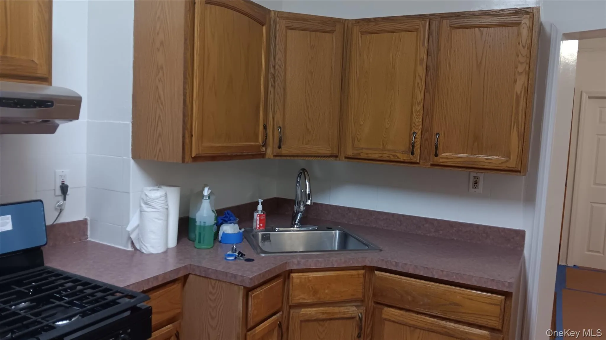 Kitchen with gas range, brown cabinets, exhaust hood, and dark countertops Kitchen with gas range, brown cabinets, exhaust hood, and dark countertops