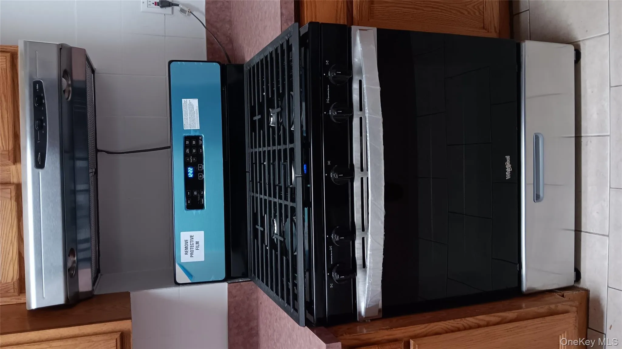 Kitchen view of brown cabinetry, stainless steel gas range, and range hood Kitchen view of brown cabinetry, stainless steel gas range, and range hood