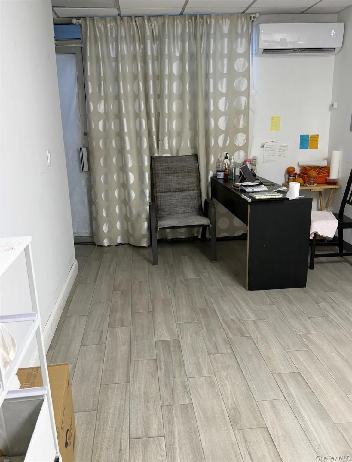 Office area with wood finish floors, a wall mounted air conditioner, and a paneled ceiling Office area with wood finish floors, a wall mounted air conditioner, and a paneled ceiling
