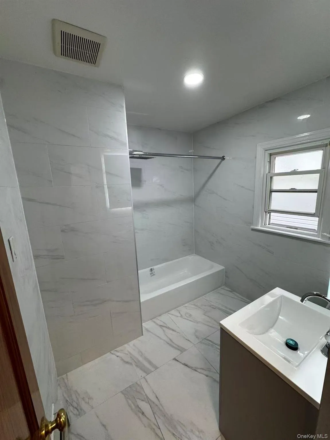 Full bathroom featuring vanity, light marble finish floors, bathing tub / shower combination, and recessed lighting Full bathroom featuring vanity, light marble finish floors, bathing tub / shower combination, and recessed lighting