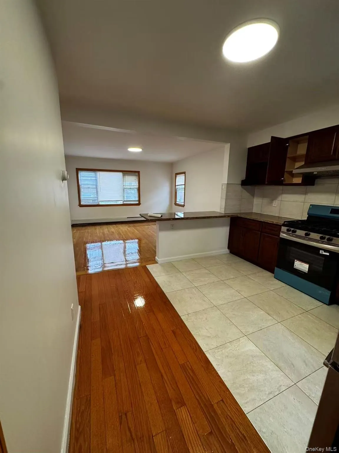 Kitchen with gas stove, light wood-type flooring, a peninsula, dark brown cabinetry, and backsplash Kitchen with gas stove, light wood-type flooring, a peninsula, dark brown cabinetry, and backsplash