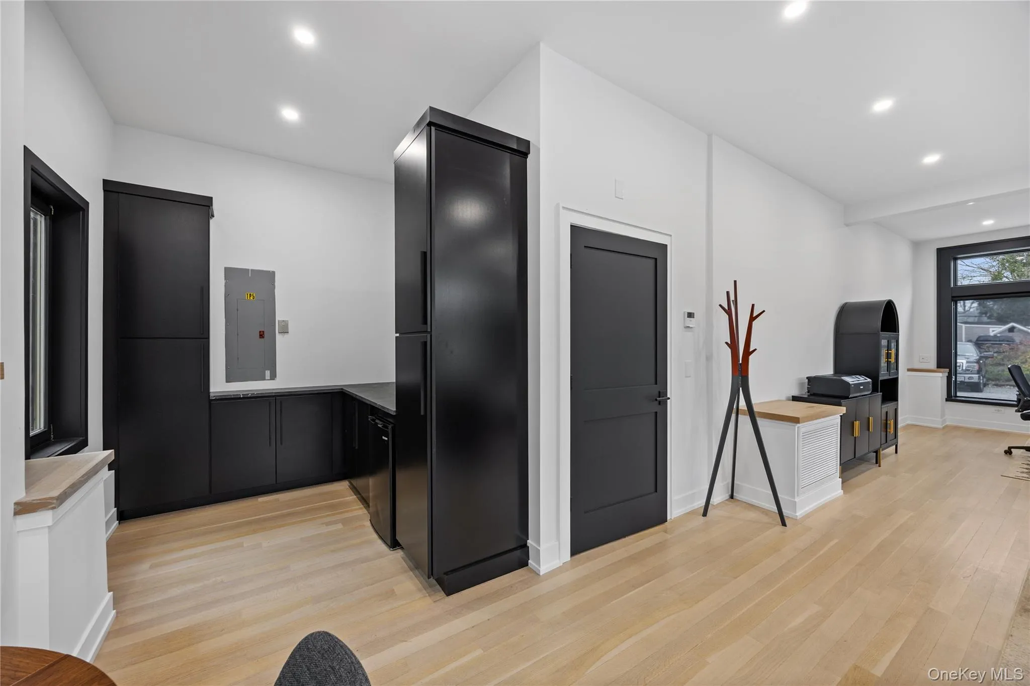 Kitchen featuring dark cabinetry, recessed lighting, light wood finished floors, and electric panel Kitchen featuring dark cabinetry, recessed lighting, light wood finished floors, and electric panel
