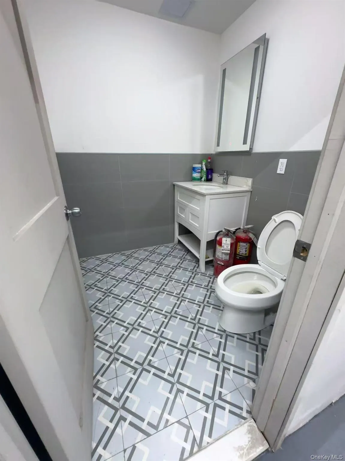 Half bath featuring vanity, tile walls, and wainscoting Half bath featuring vanity, tile walls, and wainscoting