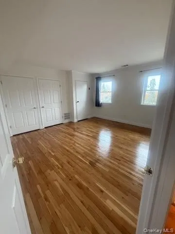 Unfurnished bedroom with light wood-style flooring and multiple closets Unfurnished bedroom with light wood-style flooring and multiple closets