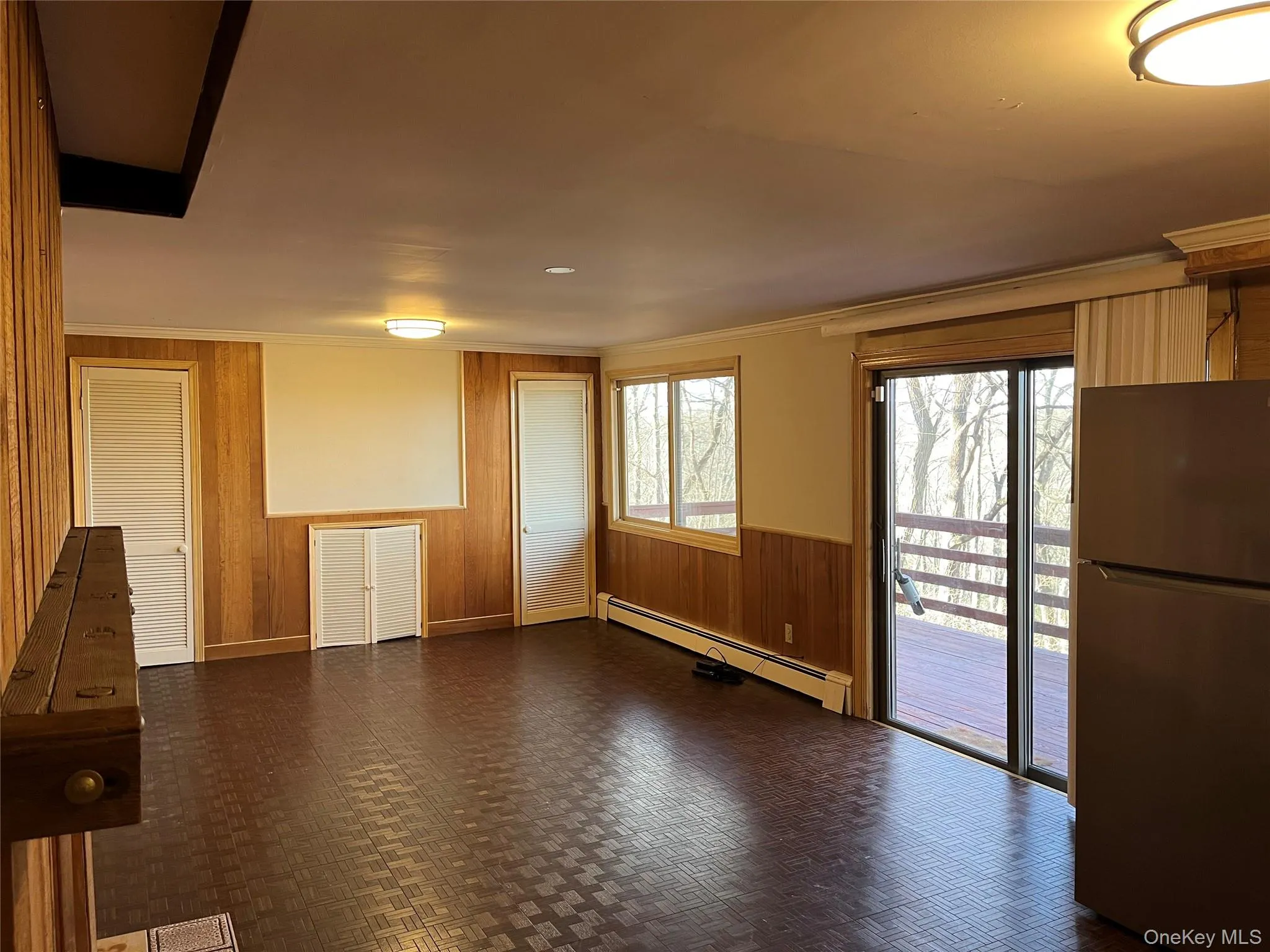 Living room with wooden walls, a wainscoted wall, sliding glass door to deck Living room with wooden walls, a wainscoted wall, sliding glass door to deck