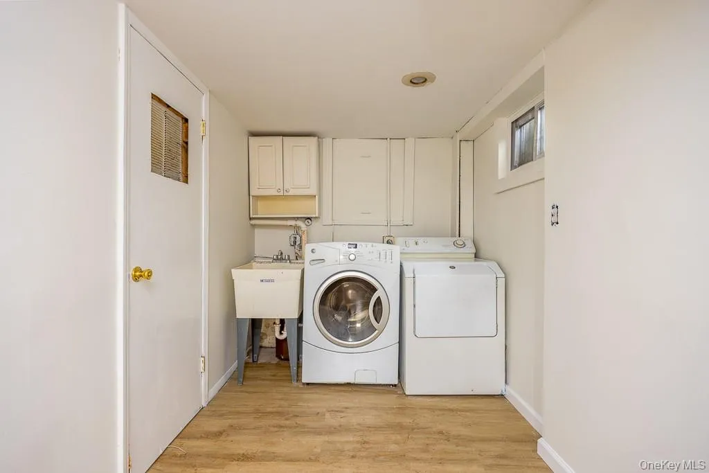 Laundry area with washing machine and dryer, light wood finished floors, and cabinet space Laundry area with washing machine and dryer, light wood finished floors, and cabinet space