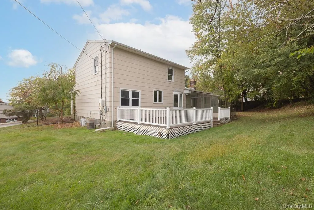 Back of house featuring a yard, a wooden deck, and a sunroom Back of house featuring a yard, a wooden deck, and a sunroom