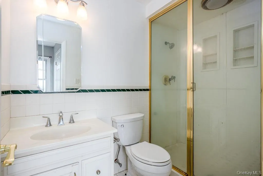 Full bathroom with tile walls, vanity, a stall shower, and wainscoting Full bathroom with tile walls, vanity, a stall shower, and wainscoting