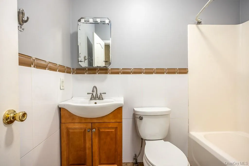 Bathroom featuring vanity, washtub / shower combination, and tile walls Bathroom featuring vanity, washtub / shower combination, and tile walls