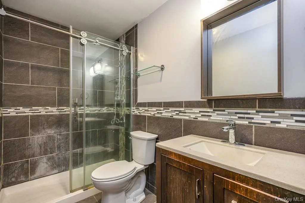 Full bathroom featuring vanity, tile walls, and a stall shower Full bathroom featuring vanity, tile walls, and a stall shower