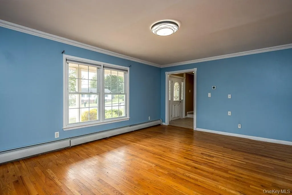 Unfurnished room with a baseboard heating unit, crown molding, and light wood finished floors Unfurnished room with a baseboard heating unit, crown molding, and light wood finished floors