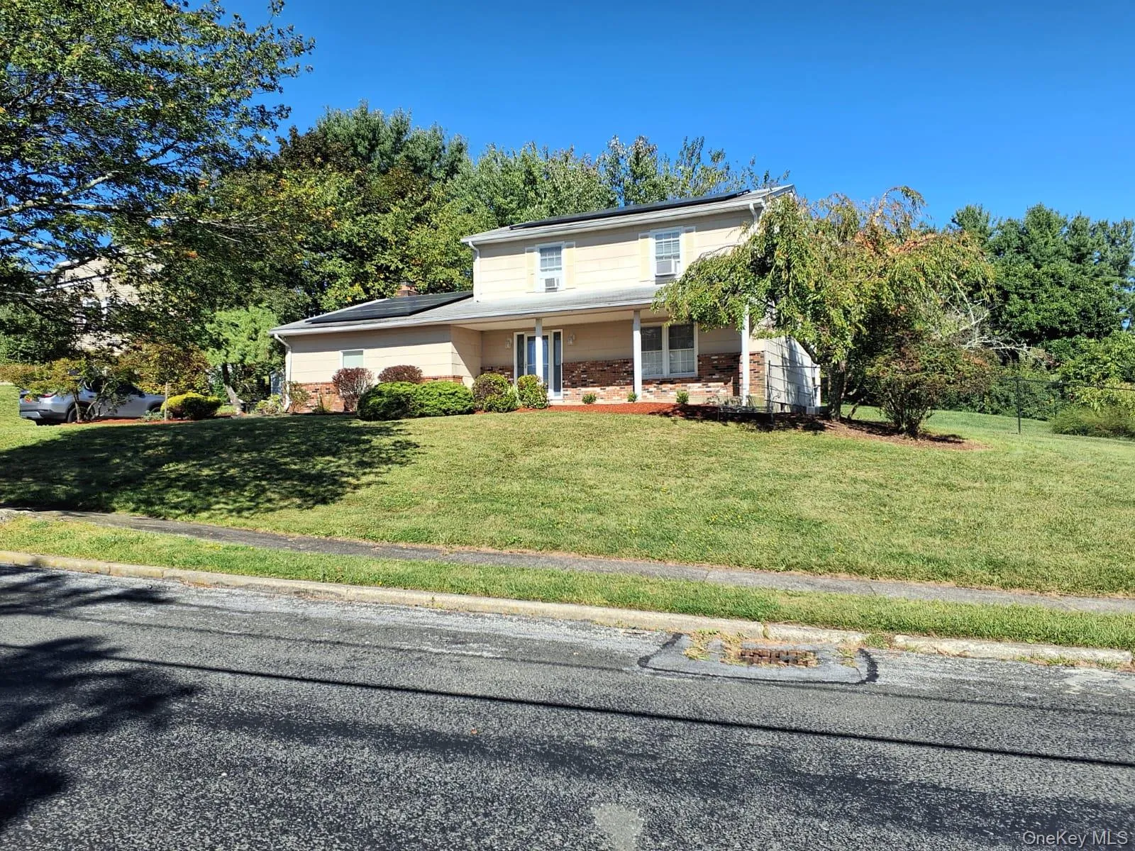 Traditional-style house featuring roof mounted solar panels, a porch, and a front yard Traditional-style house featuring roof mounted solar panels, a porch, and a front yard