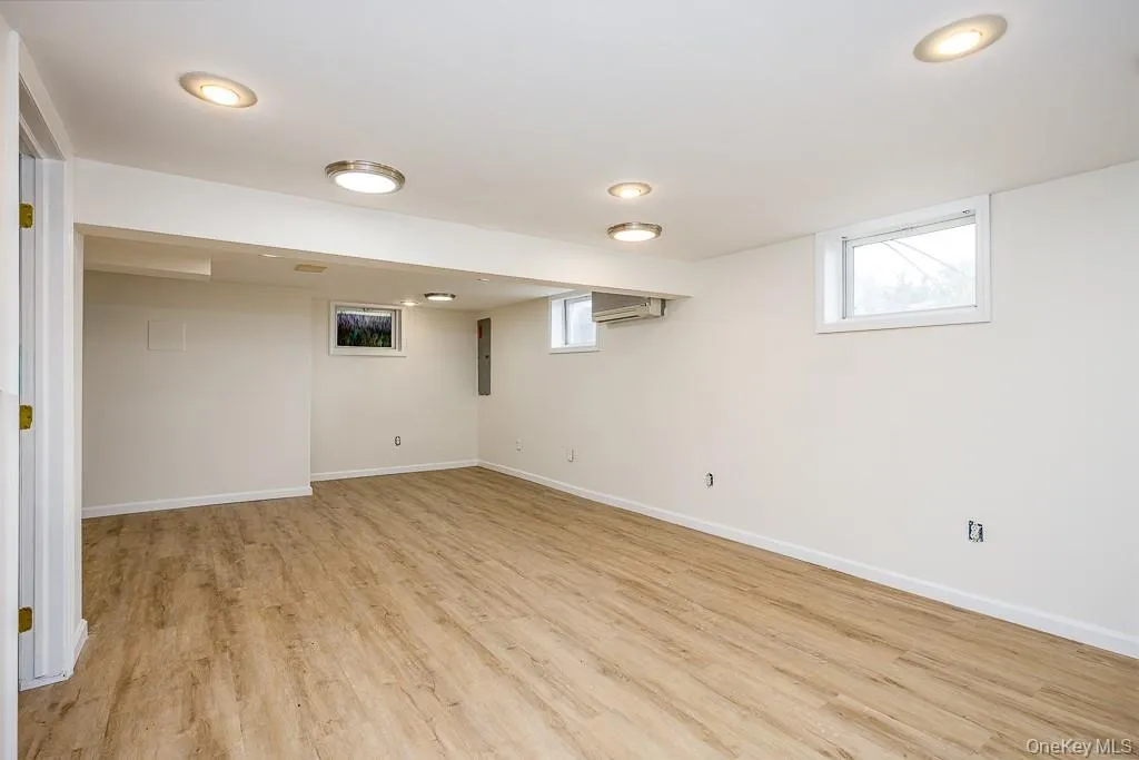 Basement with light wood finished floors and a wall mounted air conditioner Basement with light wood finished floors and a wall mounted air conditioner