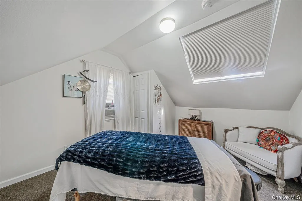 Carpeted bedroom with lofted ceiling and baseboards Carpeted bedroom with lofted ceiling and baseboards