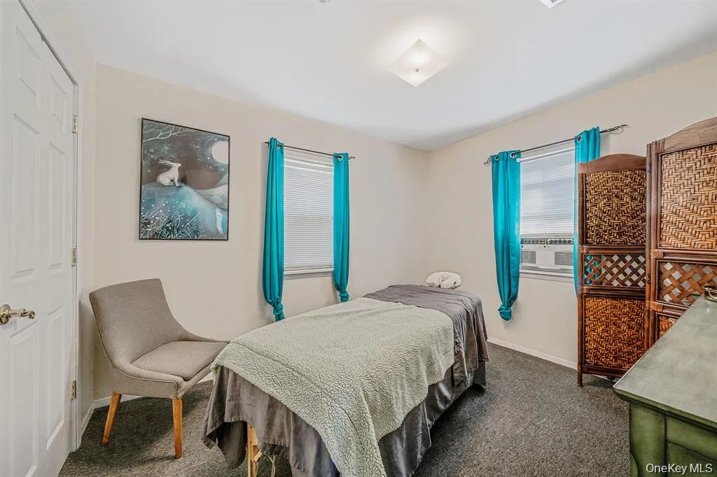 Carpeted bedroom with cooling unit and baseboards Carpeted bedroom with cooling unit and baseboards