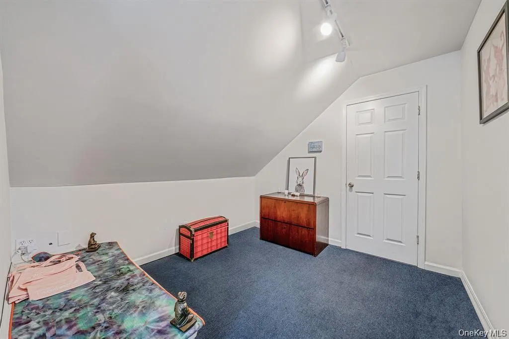 Bedroom with vaulted ceiling, rail lighting, and dark colored carpet Bedroom with vaulted ceiling, rail lighting, and dark colored carpet