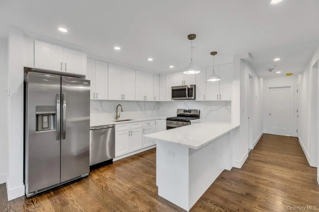 Kitchen featuring appliances with stainless steel finishes, a peninsula, pendant lighting, white cabinetry Kitchen featuring appliances with stainless steel finishes, a peninsula, pendant lighting, white cabinetry