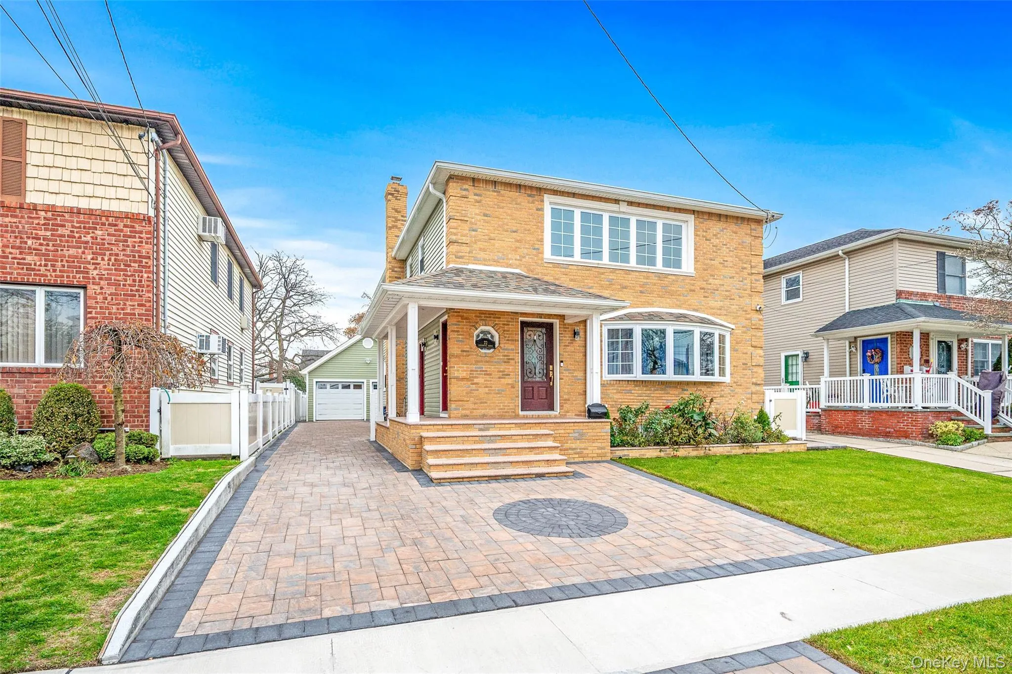 Traditional-style home with brick siding, a chimney, a porch, a detached garage, and driveway Traditional-style home with brick siding, a chimney, a porch, a detached garage, and driveway