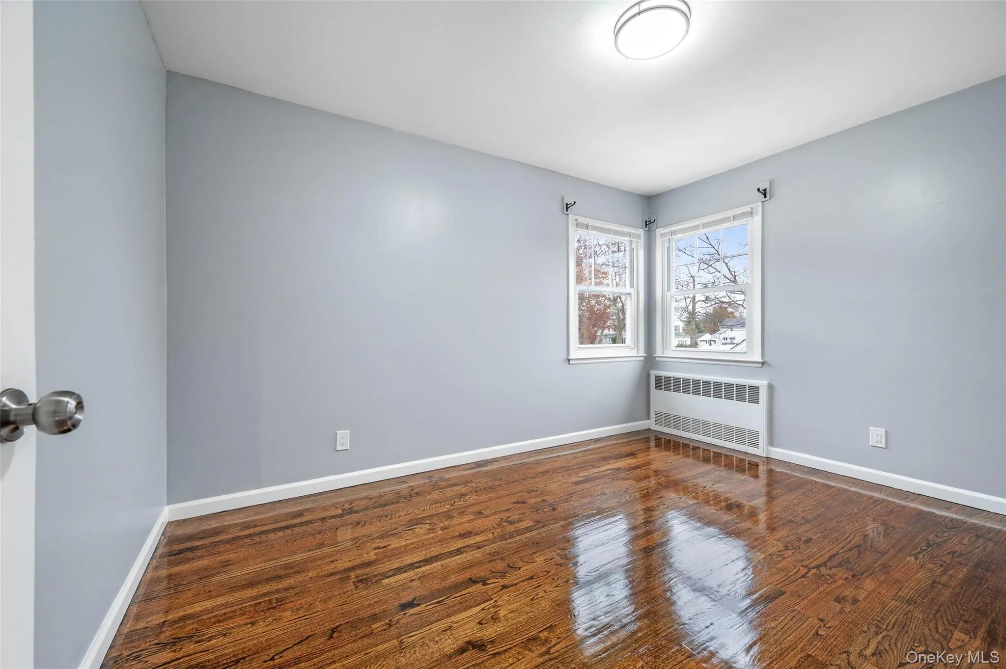 Empty room with radiator and dark wood-style flooring Empty room with radiator and dark wood-style flooring