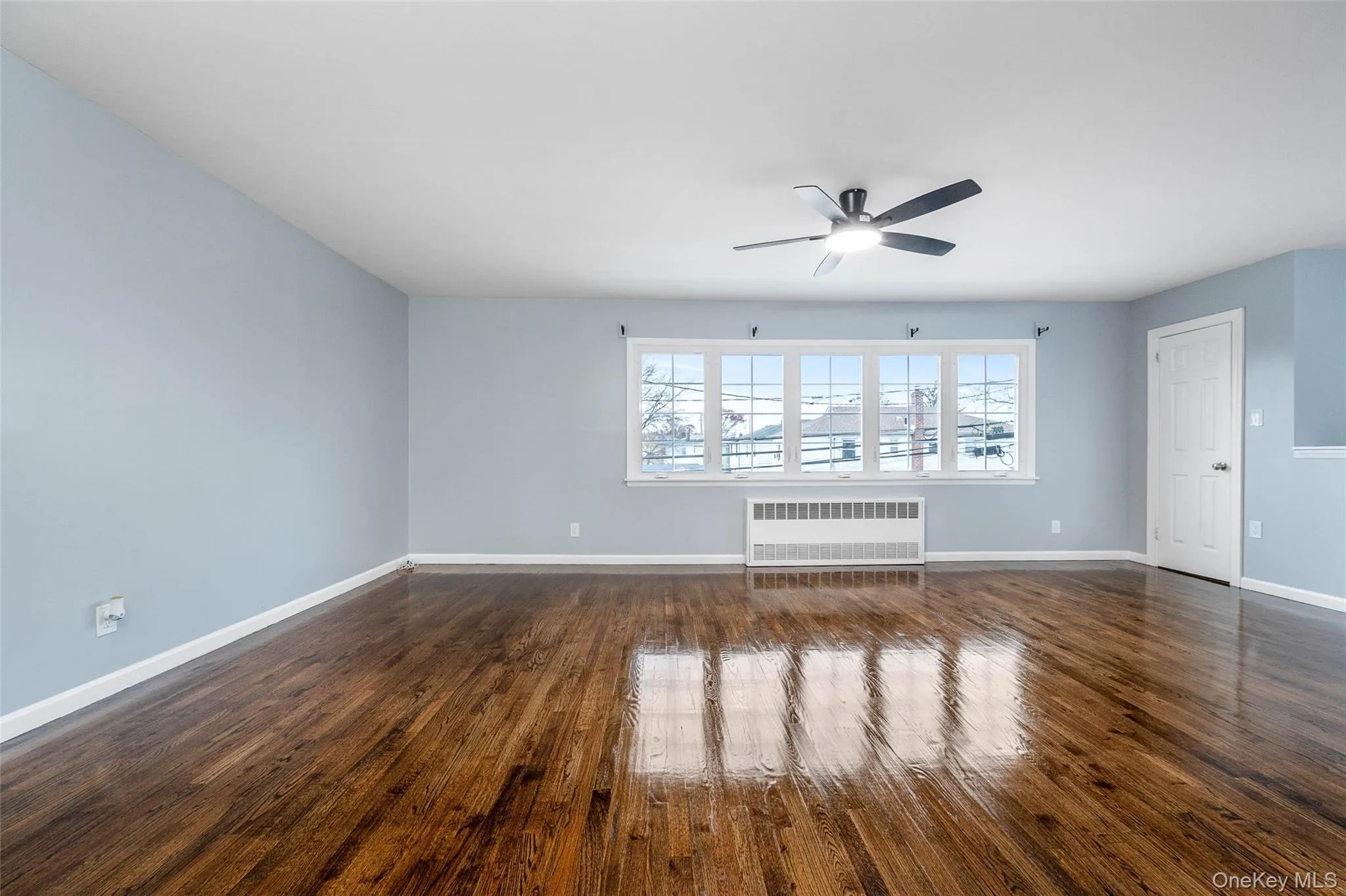 Unfurnished room with dark wood-style flooring, radiator heating unit, and a ceiling fan Unfurnished room with dark wood-style flooring, radiator heating unit, and a ceiling fan