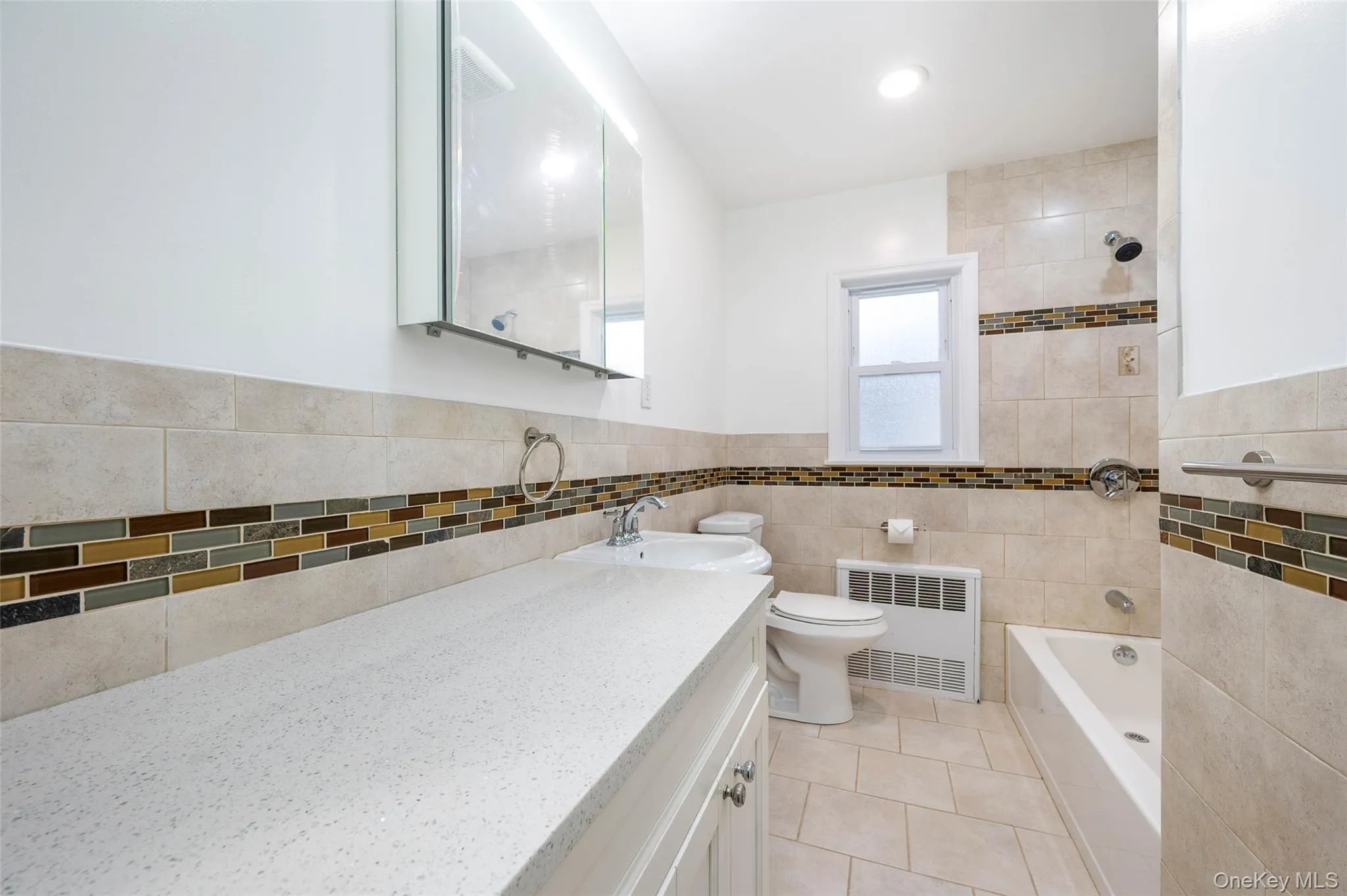 Bathroom with radiator heating unit, shower / tub combination, light tile patterned flooring, tile walls, and vanity Bathroom with radiator heating unit, shower / tub combination, light tile patterned flooring, tile walls, and vanity