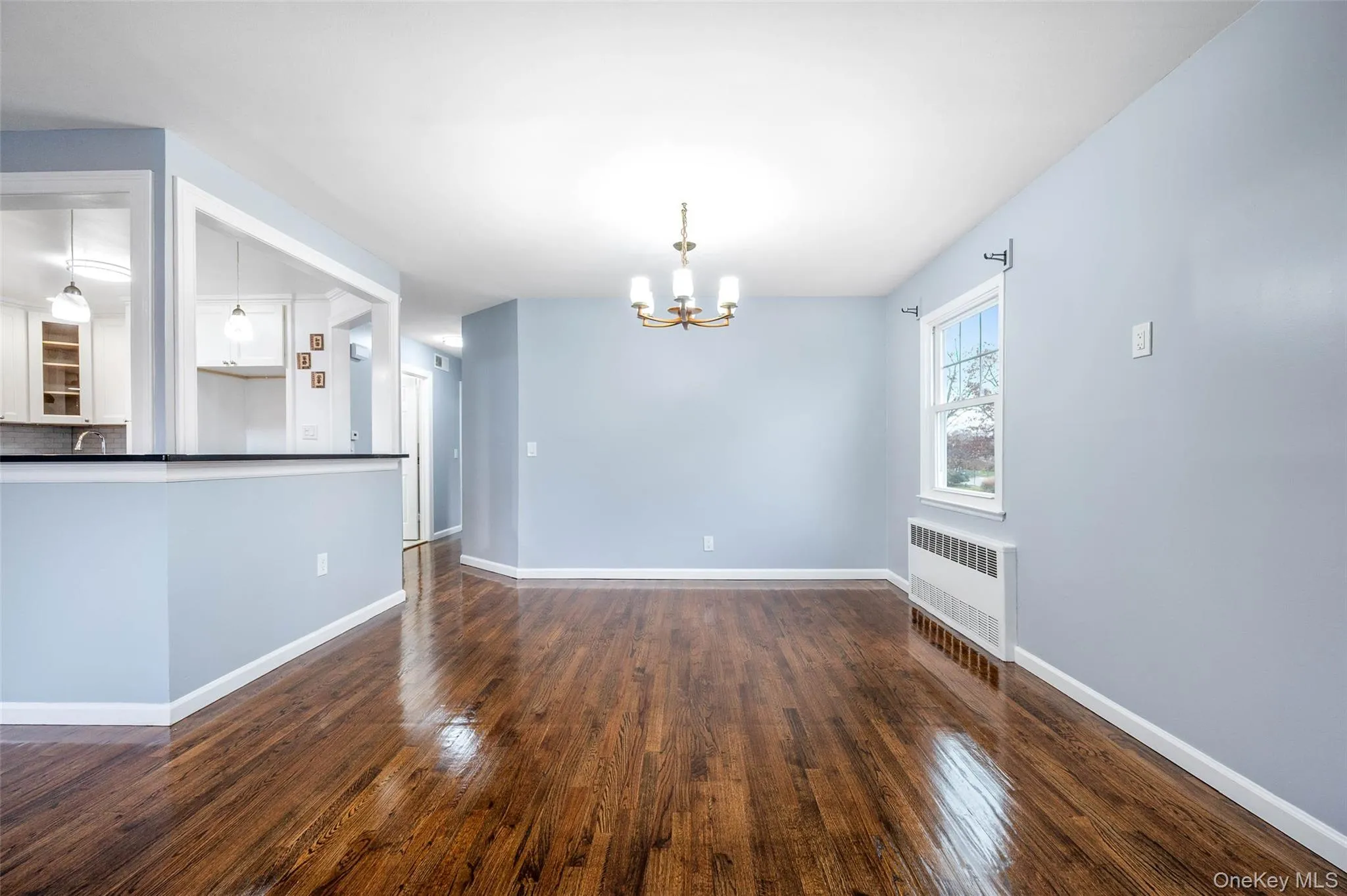 Unfurnished dining area featuring radiator, a chandelier, and dark wood finished floors Unfurnished dining area featuring radiator, a chandelier, and dark wood finished floors
