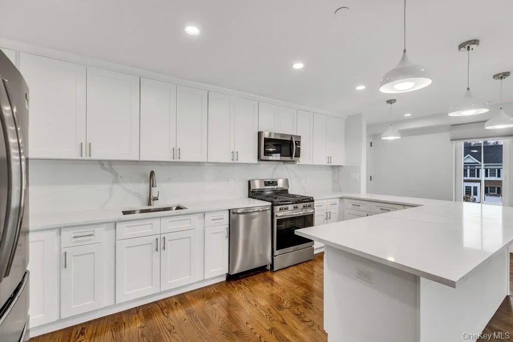 Kitchen with stainless steel appliances, white cabinetry, pendant lighting Kitchen with stainless steel appliances, white cabinetry, pendant lighting