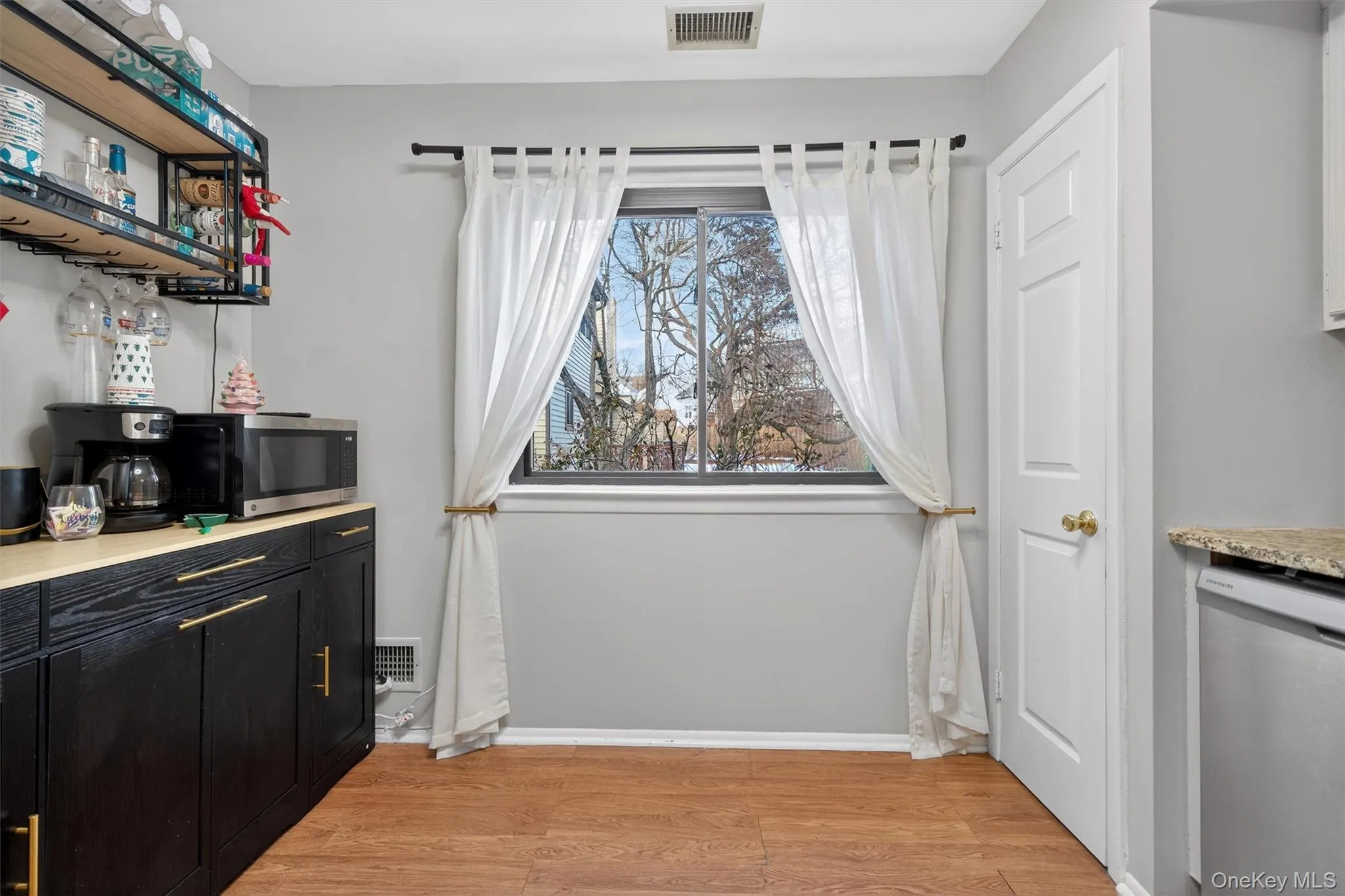 Bar with appliances with stainless steel finishes, light wood-style flooring, dark cabinetry, open shelves, and light stone counters Bar with appliances with stainless steel finishes, light wood-style flooring, dark cabinetry, open shelves, and light stone counters
