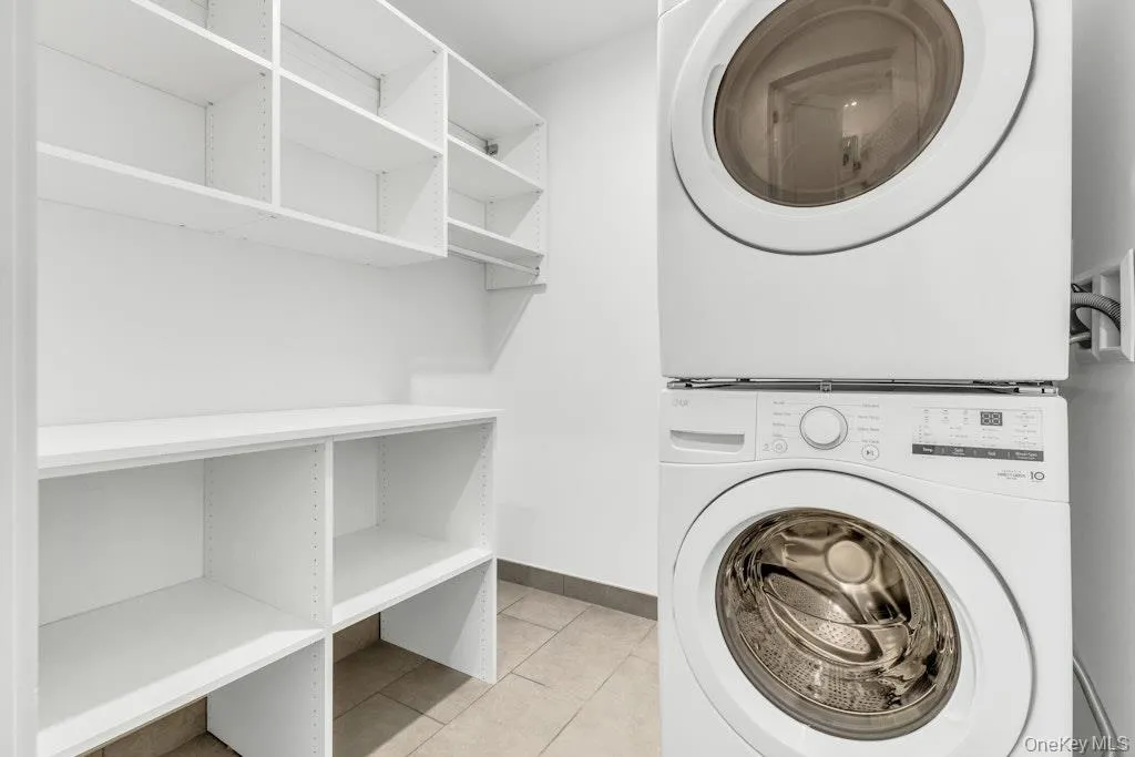Laundry area featuring stacked washer and clothes dryer and shelving Laundry area featuring stacked washer and clothes dryer and shelving