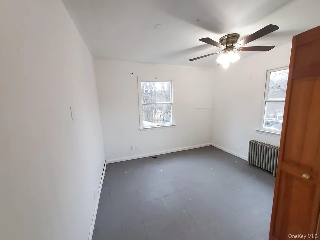 Spare room featuring radiator heating unit, ceiling fan, and tile patterned floors Spare room featuring radiator heating unit, ceiling fan, and tile patterned floors