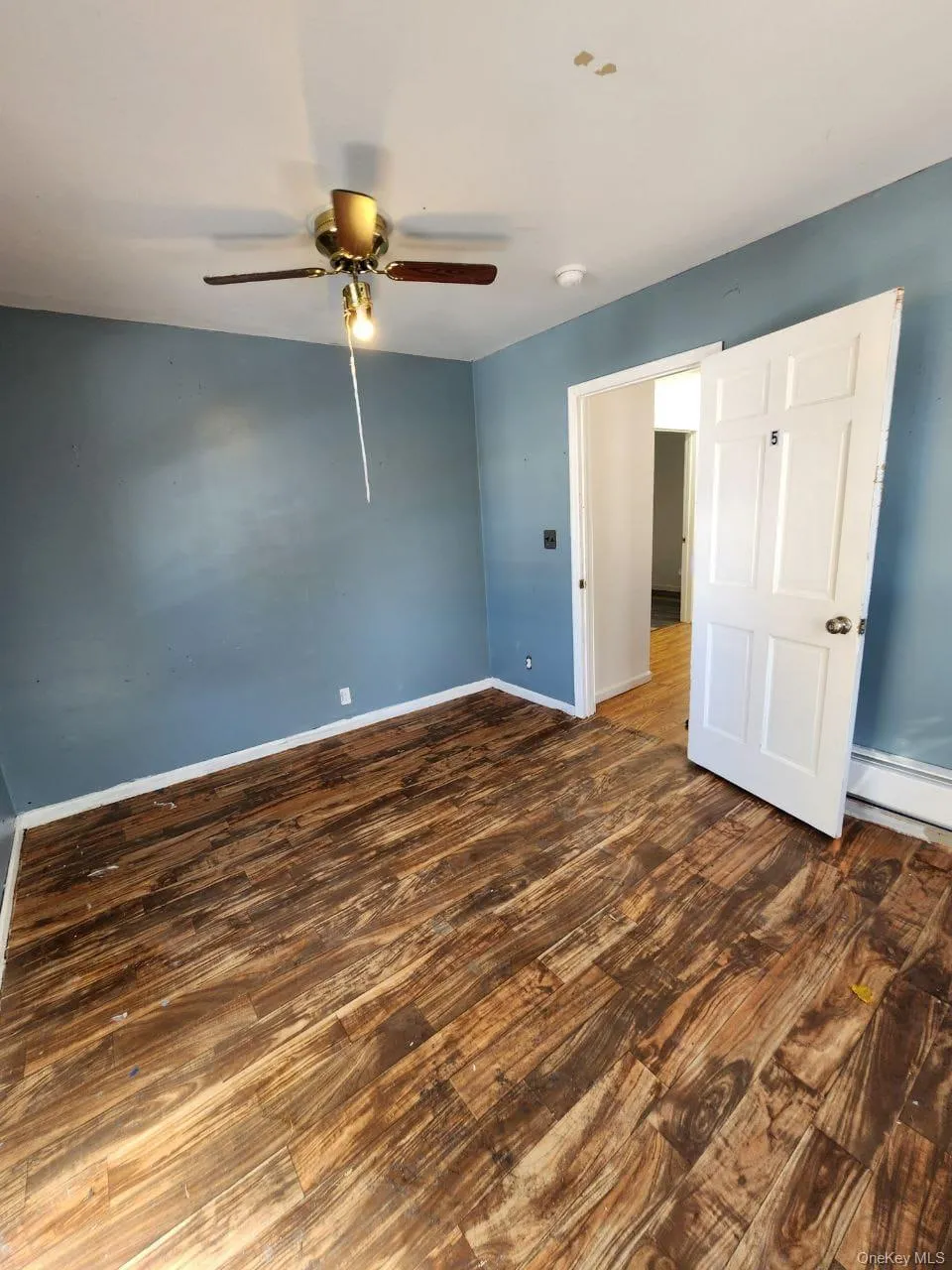 Spare room with dark wood-type flooring, baseboard heating, and a ceiling fan Spare room with dark wood-type flooring, baseboard heating, and a ceiling fan