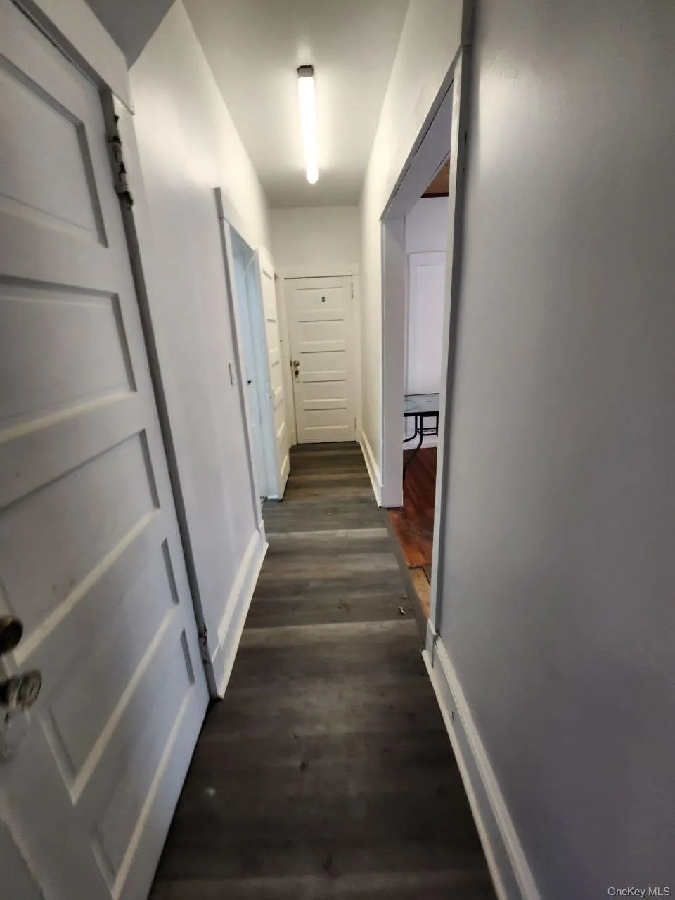 Hallway featuring baseboards and dark wood-style flooring Hallway featuring baseboards and dark wood-style flooring