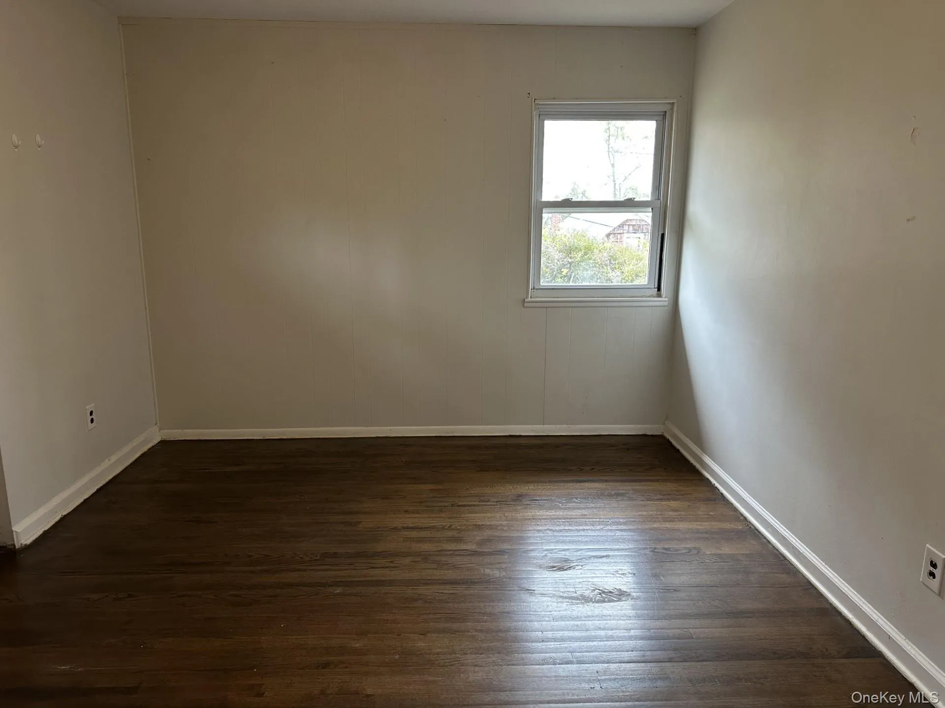 Empty room featuring dark wood-style flooring and baseboards Empty room featuring dark wood-style flooring and baseboards