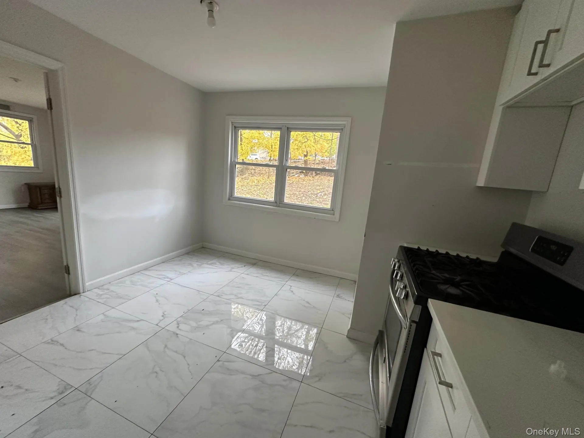 Kitchen with white cabinetry, stainless steel gas range, and light marble finish floors Kitchen with white cabinetry, stainless steel gas range, and light marble finish floors