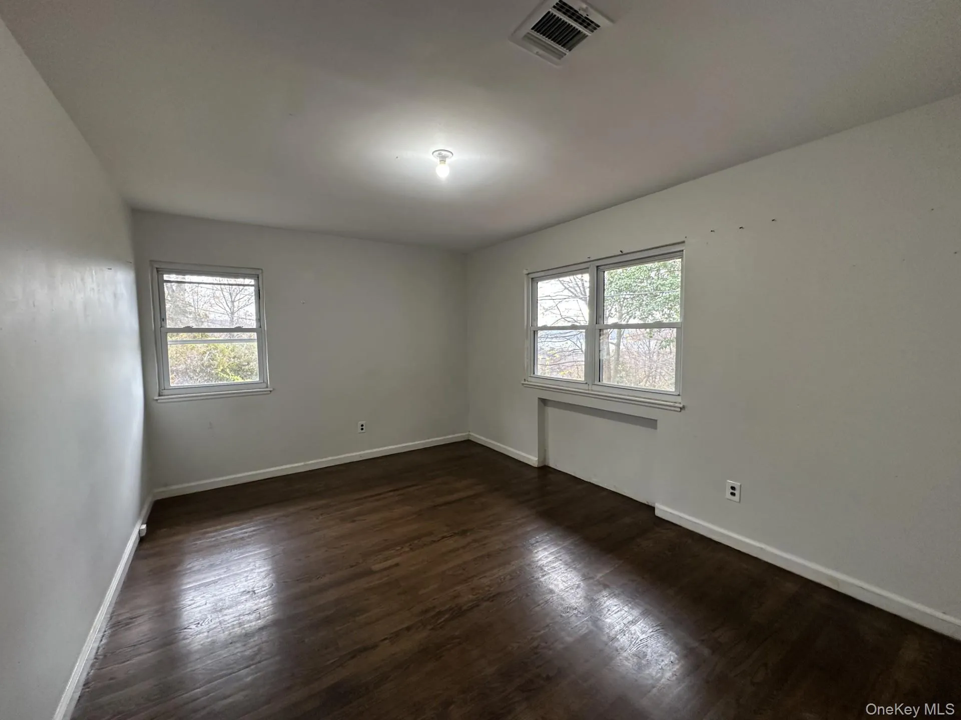 Spare room with plenty of natural light and dark wood-style flooring Spare room with plenty of natural light and dark wood-style flooring