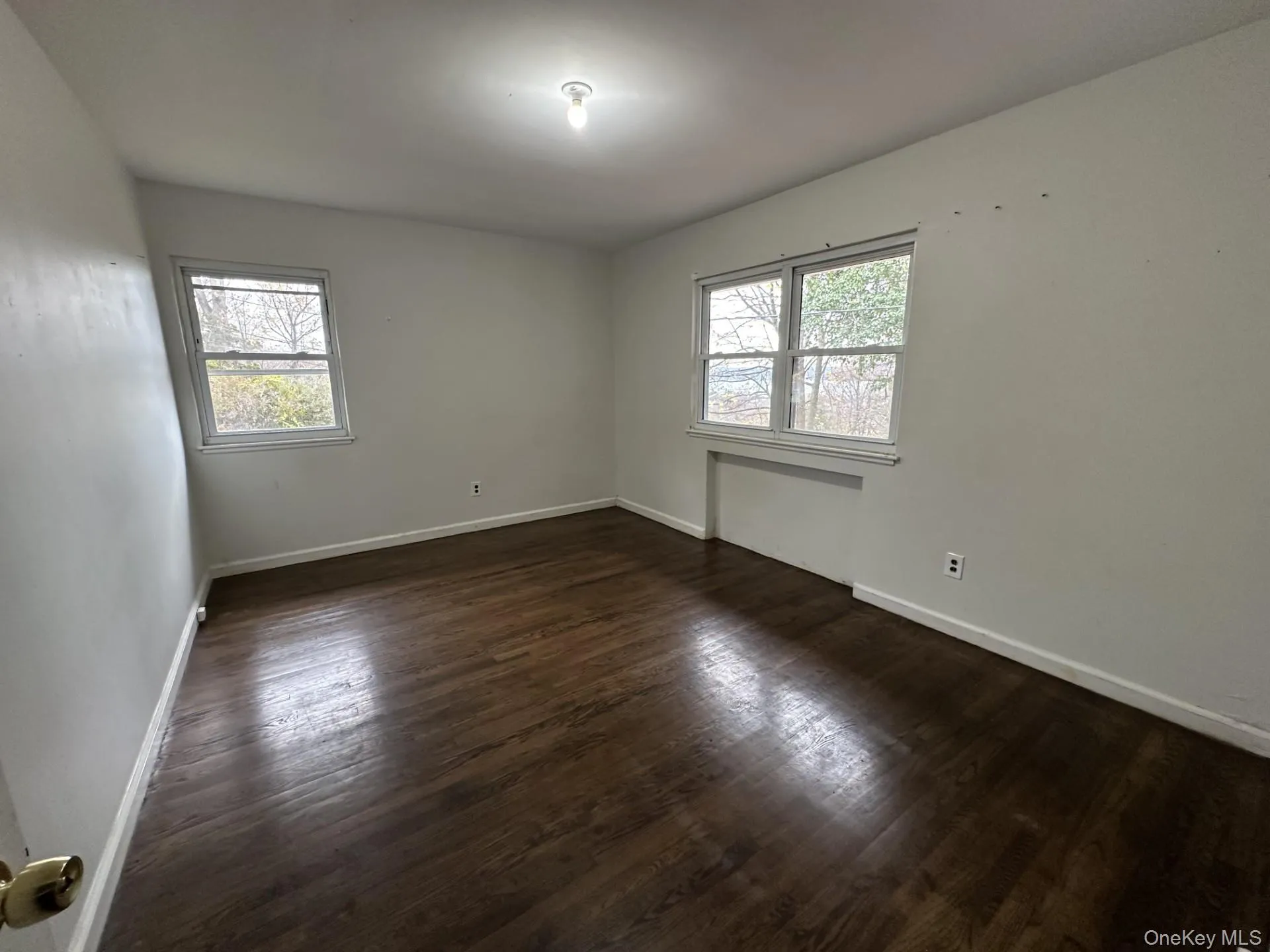 Spare room with dark wood finished floors and healthy amount of natural light Spare room with dark wood finished floors and healthy amount of natural light