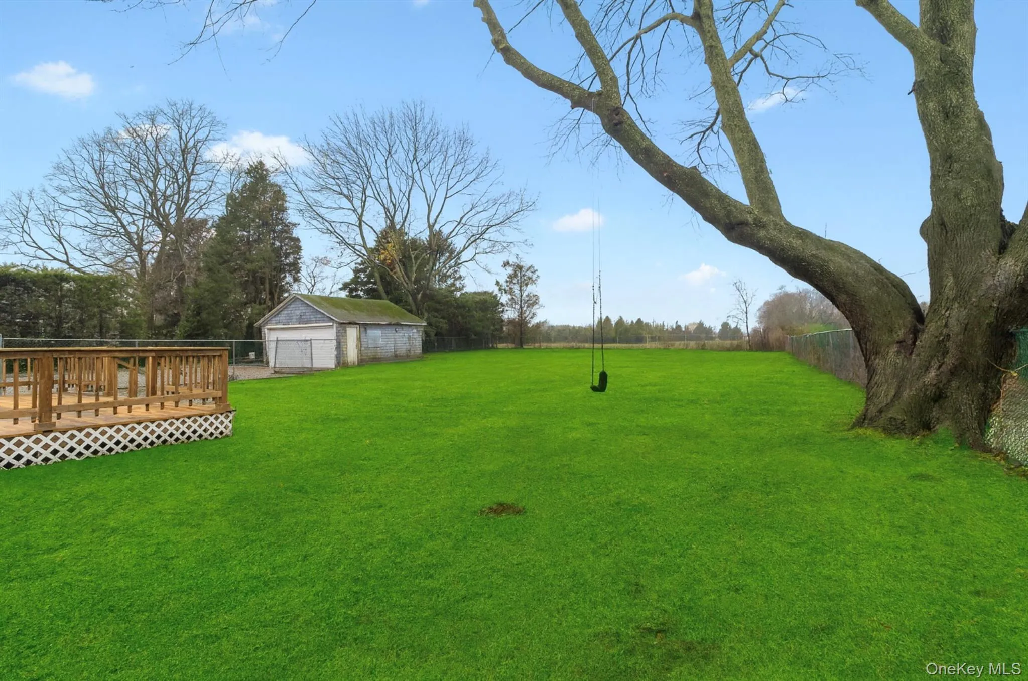 Fenced backyard with an outbuilding, a deck, and a detached garage Fenced backyard with an outbuilding, a deck, and a detached garage