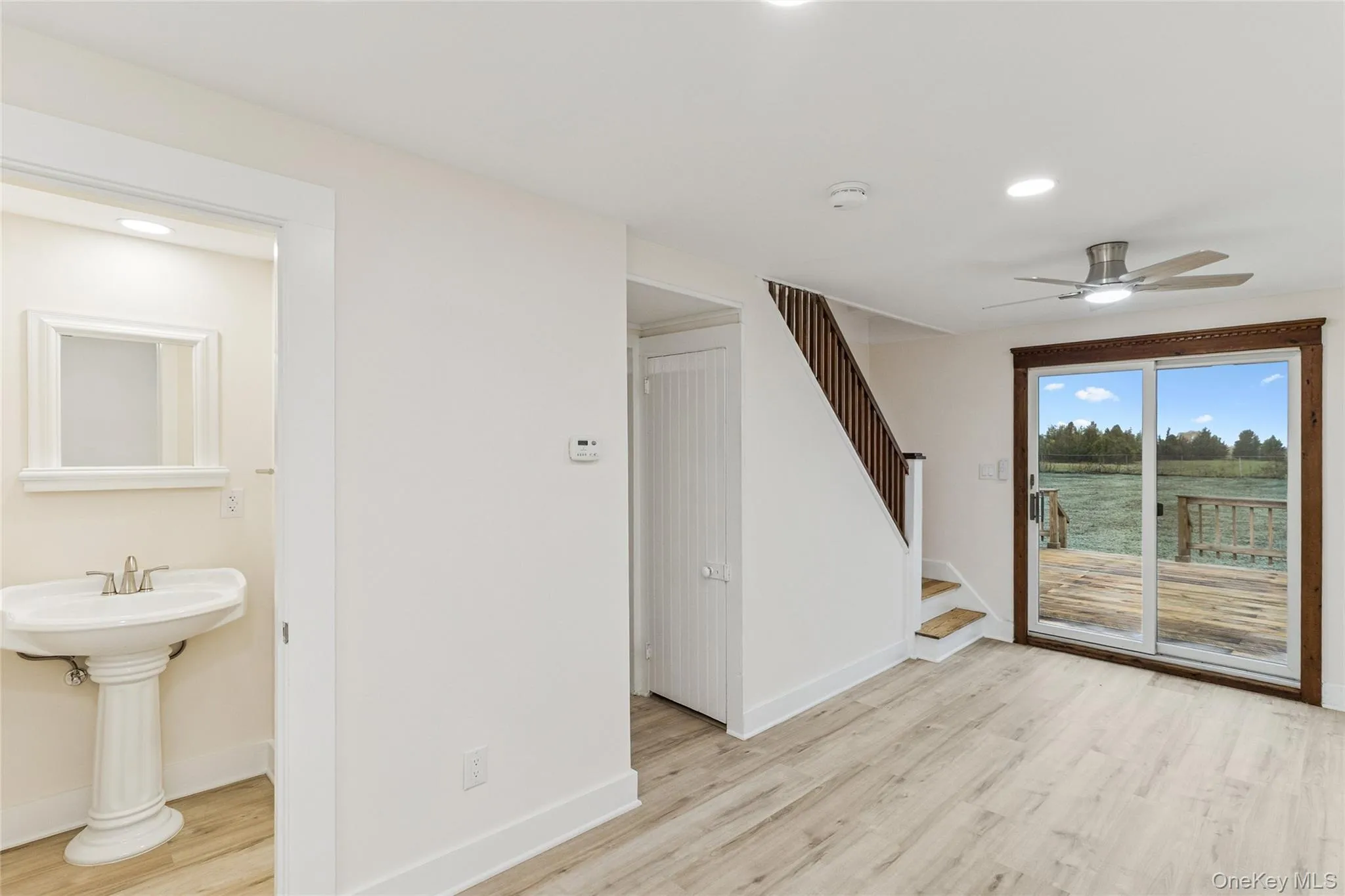 Unfurnished living room featuring light wood finished floors, stairway, a ceiling fan, recessed lighting, and a water view Unfurnished living room featuring light wood finished floors, stairway, a ceiling fan, recessed lighting, and a water view