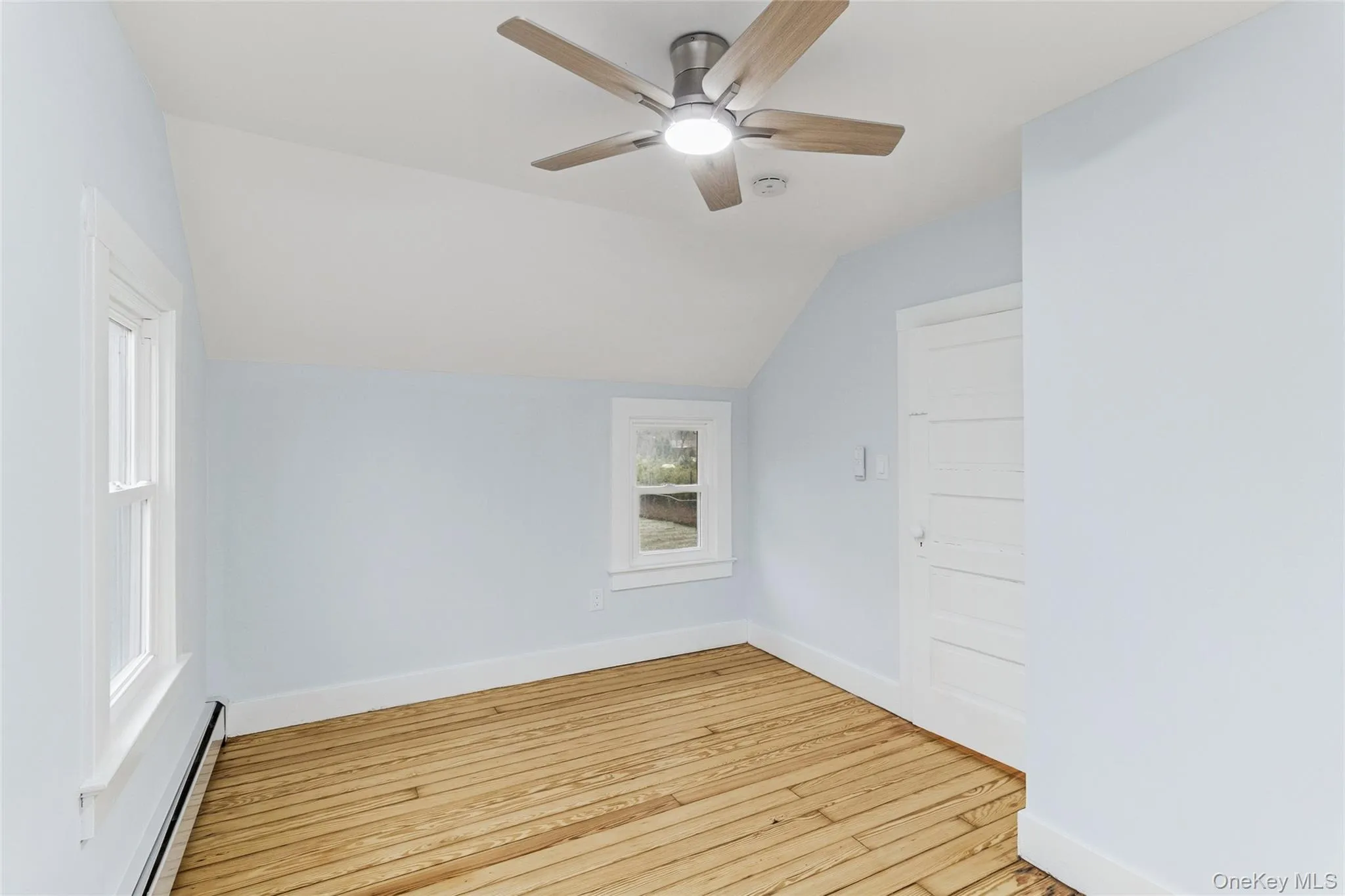 Additional living space featuring a baseboard heating unit, vaulted ceiling, light wood-style floors, and ceiling fan Additional living space featuring a baseboard heating unit, vaulted ceiling, light wood-style floors, and ceiling fan