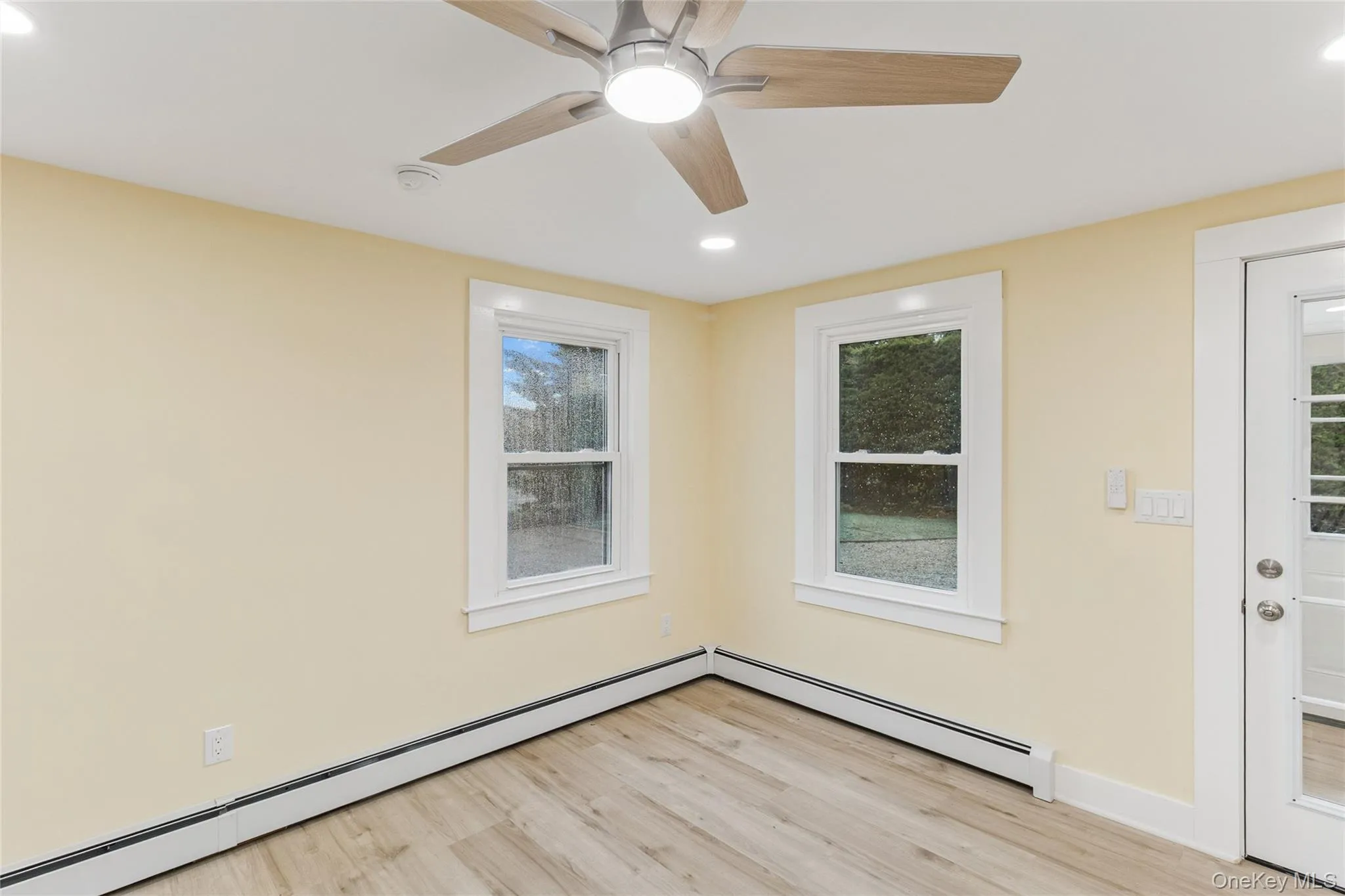 Empty room featuring a baseboard heating unit, recessed lighting, light wood-type flooring, and a ceiling fan Empty room featuring a baseboard heating unit, recessed lighting, light wood-type flooring, and a ceiling fan