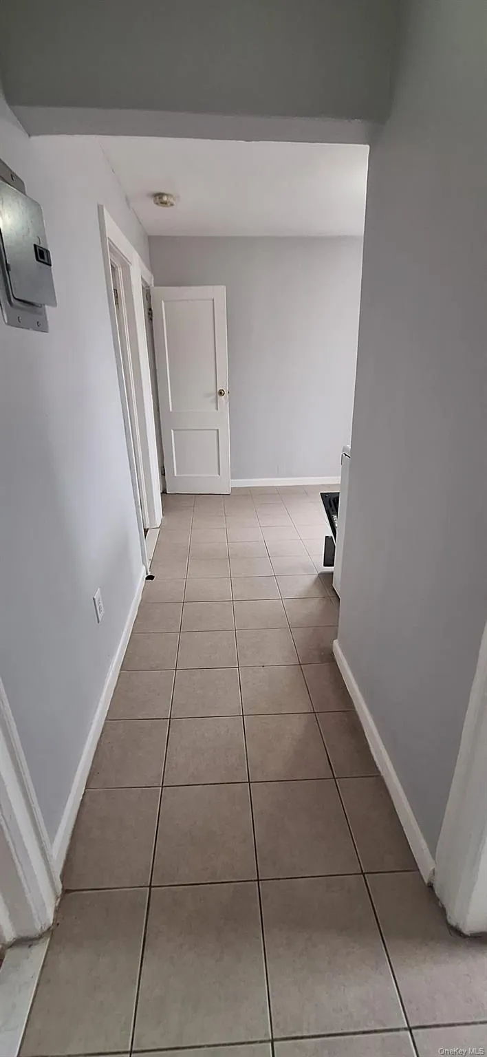 Hallway with light tile patterned flooring and baseboards Hallway with light tile patterned flooring and baseboards