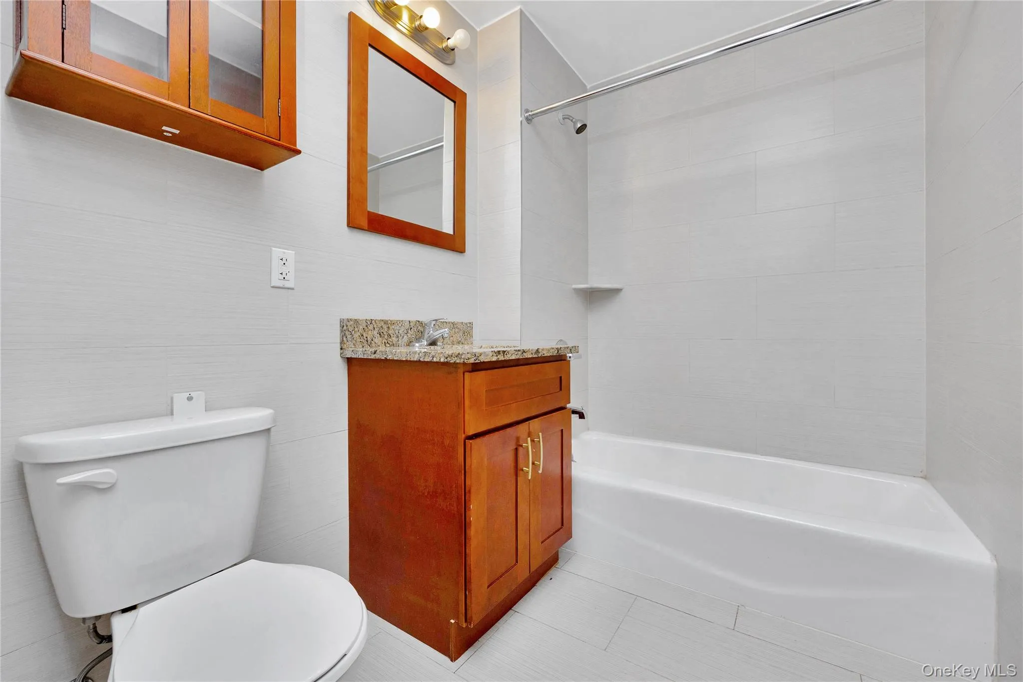 Full bath featuring vanity, toilet, shower / bath combination, tile walls, and tile patterned floors Full bath featuring vanity, toilet, shower / bath combination, tile walls, and tile patterned floors
