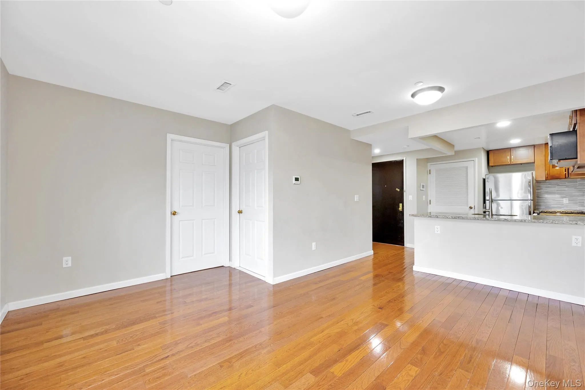 Unfurnished living room with light wood-style floors, baseboards, and visible vents Unfurnished living room with light wood-style floors, baseboards, and visible vents
