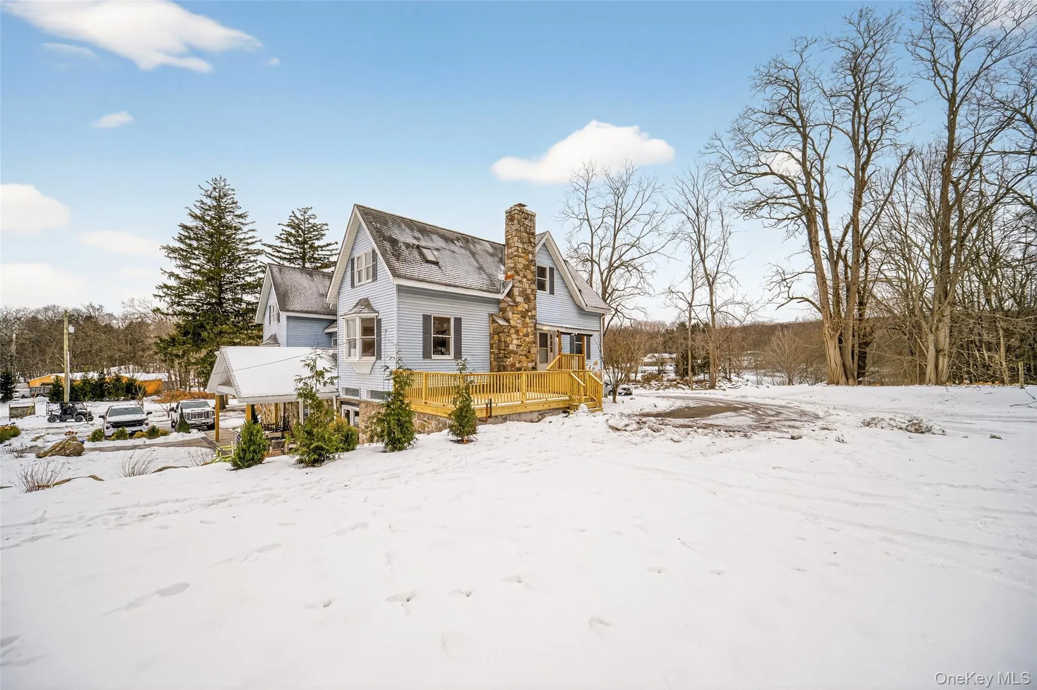 View of snow covered exterior featuring a deck and a chimney View of snow covered exterior featuring a deck and a chimney