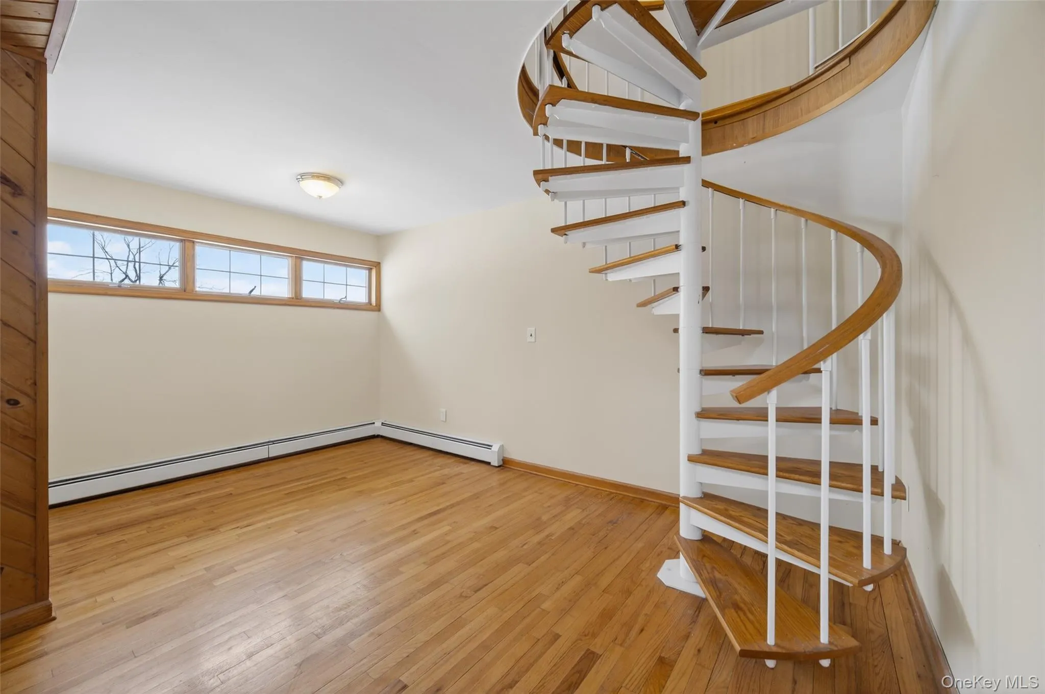 Stairs featuring wood-type flooring and baseboard heating Stairs featuring wood-type flooring and baseboard heating