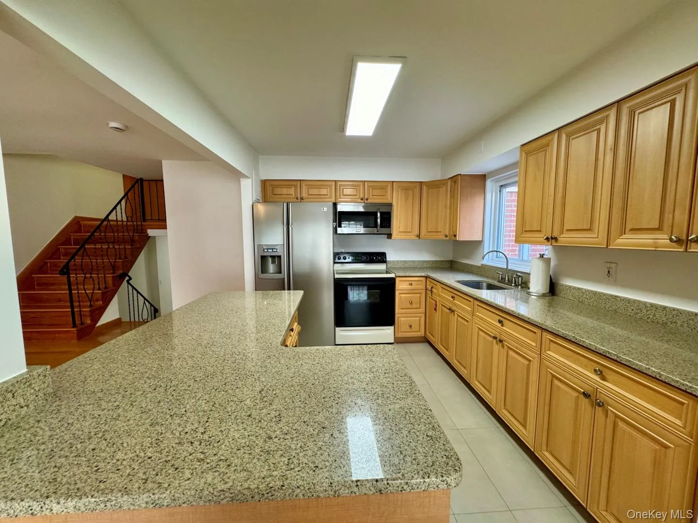 Kitchen featuring light stone countertops, stainless steel appliances, and light tile patterned flooring Kitchen featuring light stone countertops, stainless steel appliances, and light tile patterned flooring