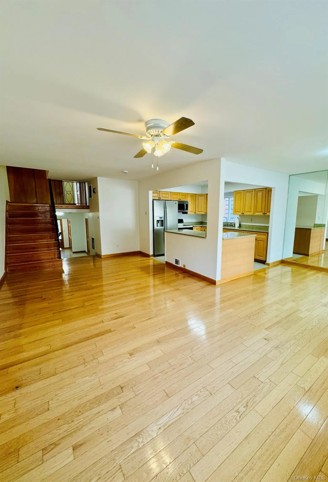 Unfurnished living room with light wood-style floors, ceiling fan, and stairway Unfurnished living room with light wood-style floors, ceiling fan, and stairway