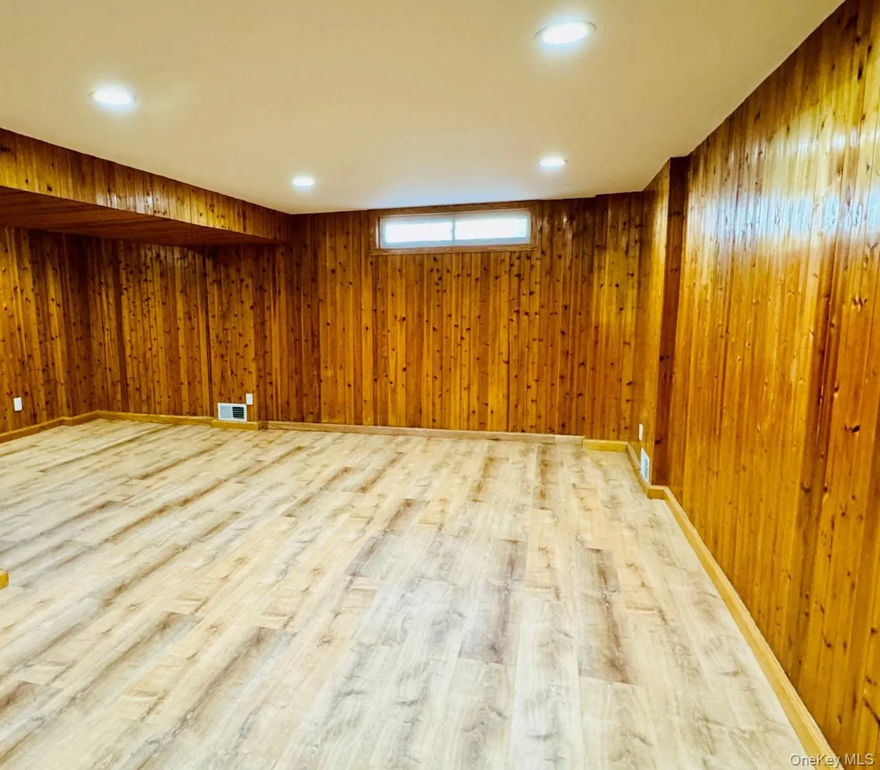 Basement featuring wood walls and light wood finished floors Basement featuring wood walls and light wood finished floors