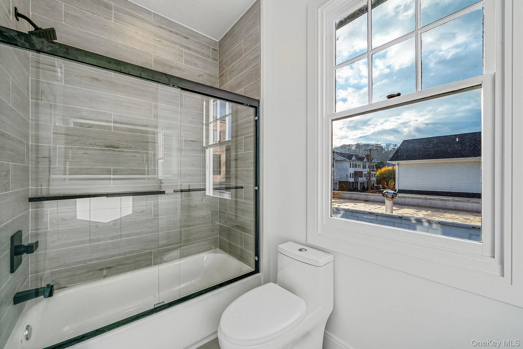 Bathroom featuring bath / shower combo with glass door and toilet Bathroom featuring bath / shower combo with glass door and toilet